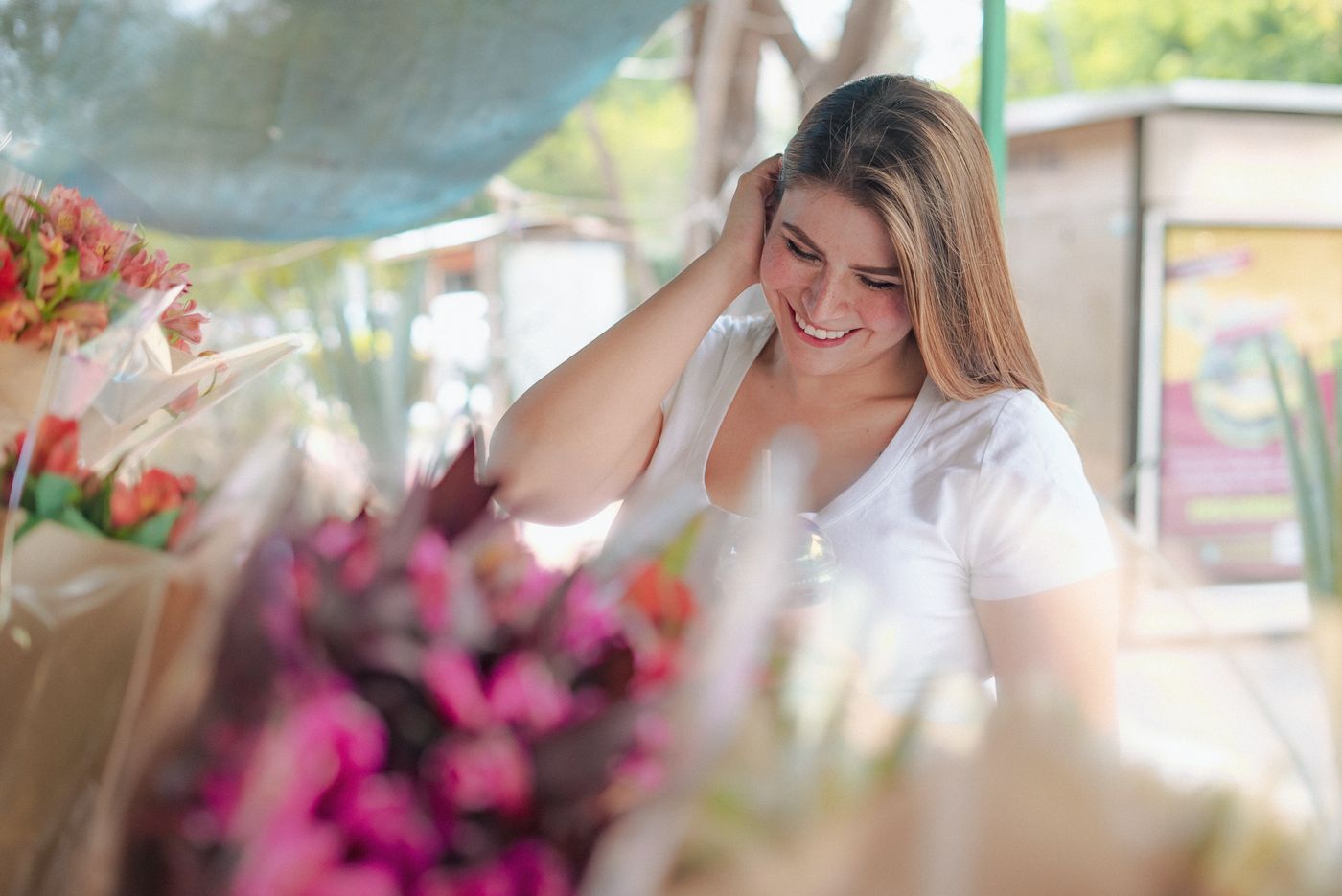 A woman smiling as she chooses flowers at a market