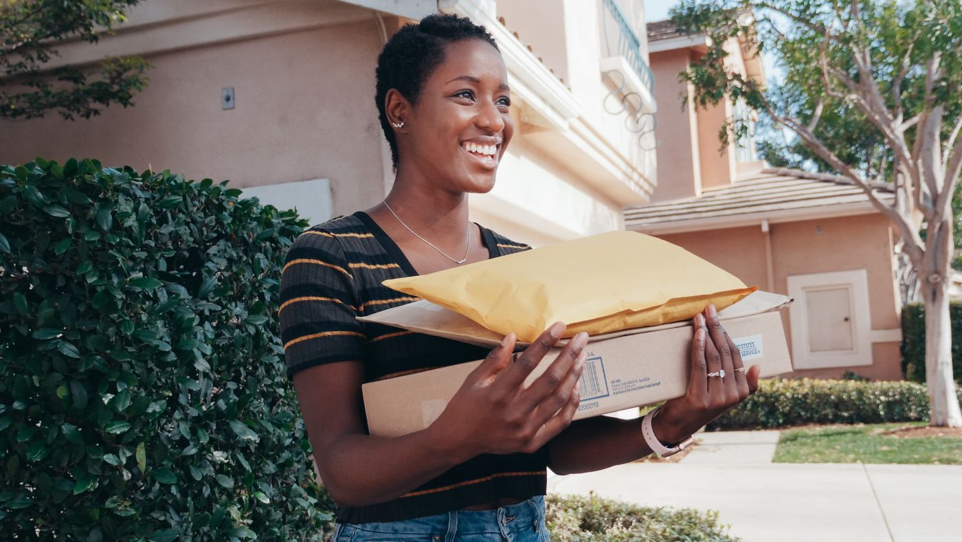 A smiling woman receiving her parcels at her front door