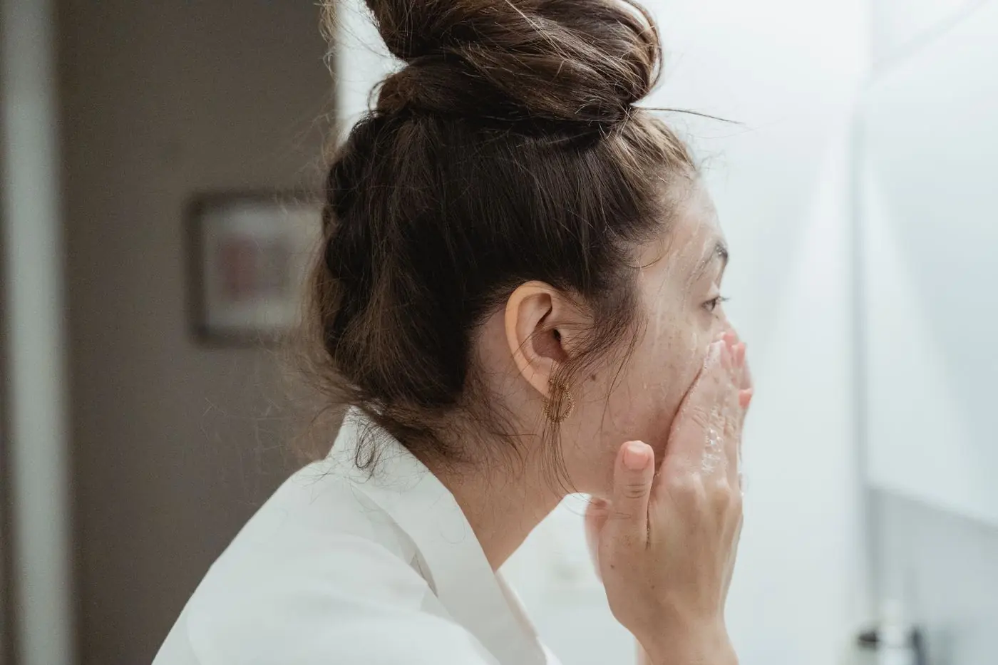 A woman smoothing cream onto her face in the morning