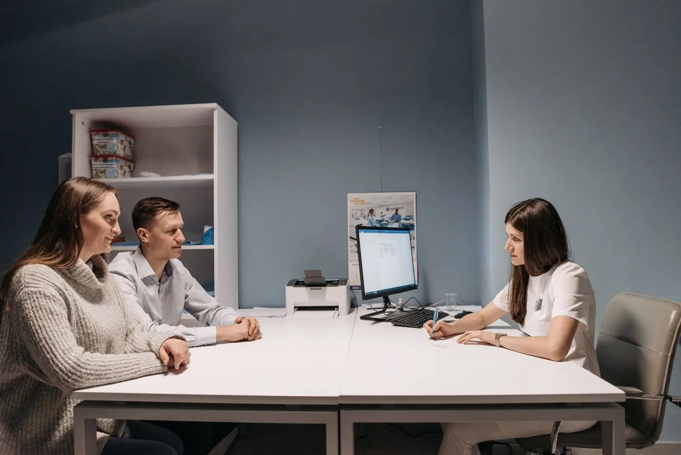 A fertility consultant talking with a couple at her desk