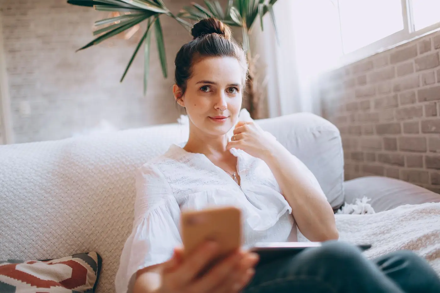 A woman smiling at her phone on the sofa