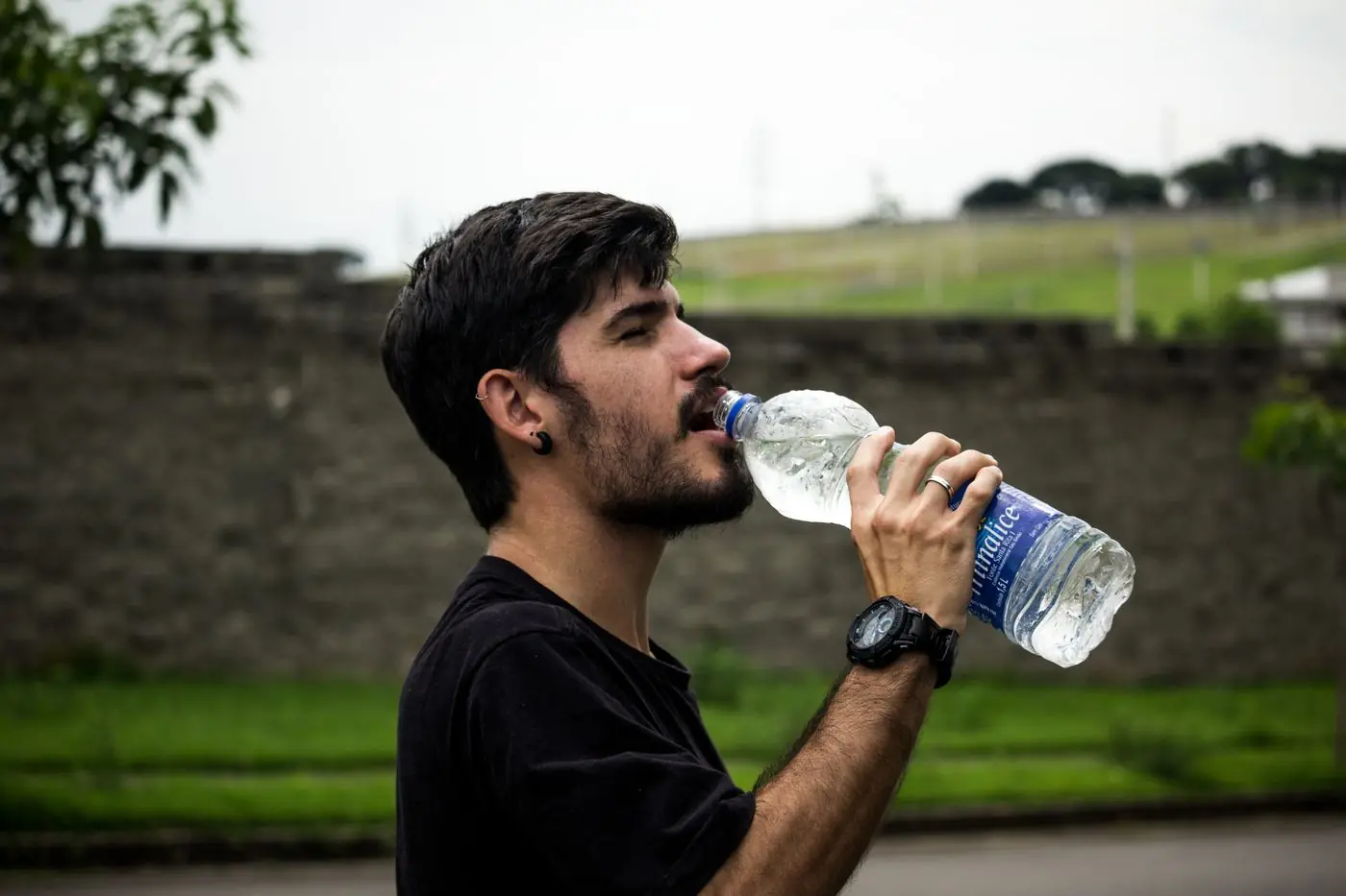 A man enjoying a drink of water outdoors after exercise