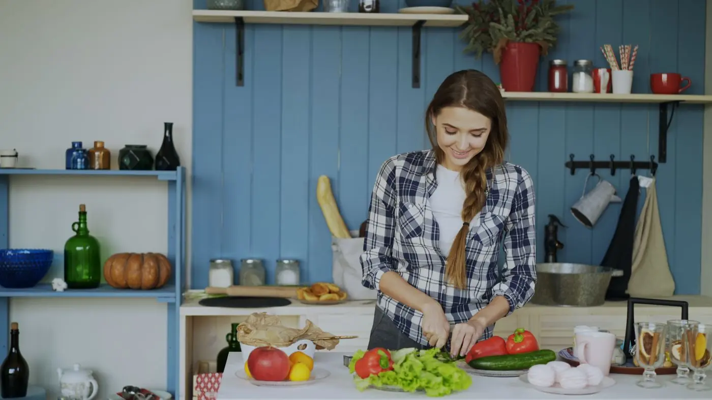 A smiling woman preparing a fresh meal in her kitchen